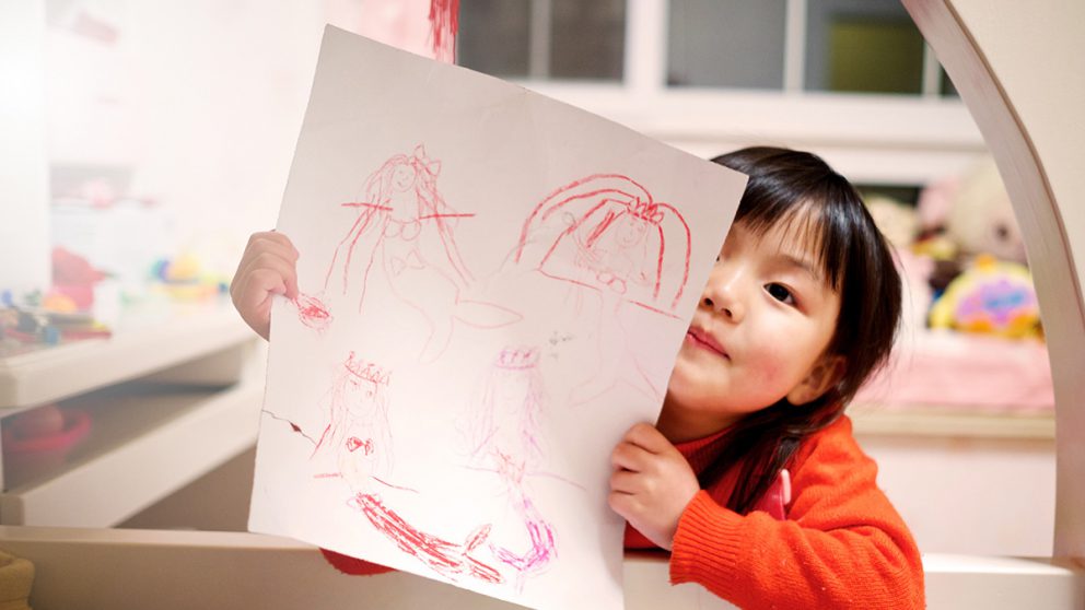 Girl showing crayon drawings